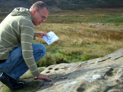 Figure 7. Participant exploring the carving through touch and visual material, Lordenshaw site visit (Rothbury, Workshop 3)
